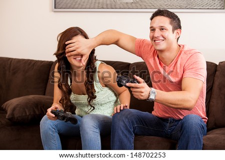 Handsome young man cheating on a video game while playing with his girlfriend