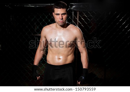 Portrait of a young MMA Fighter waiting for his fight in a fighting cage with some copy space