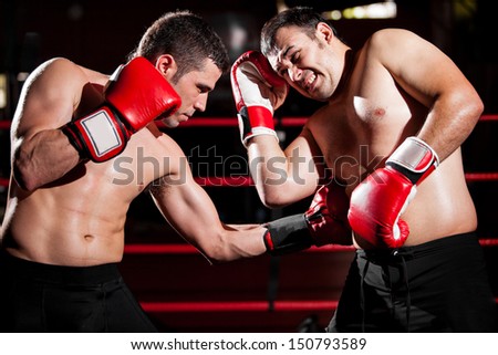 Latin boxer punching his rival in the ribs during a box fight