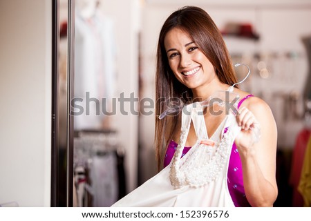 Happy Latin woman trying on a new dress in front of the mirror and smiling