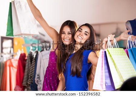 Beautiful Latin women carrying shopping bags and buying some clothes together