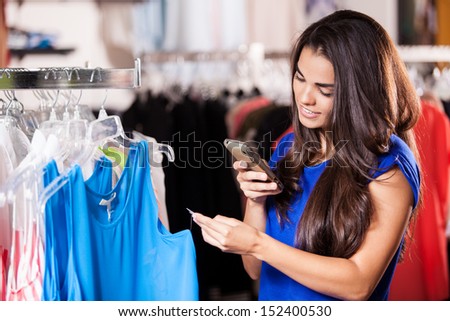 Pretty Latin woman taking a snapshot of a price tag in a clothing store