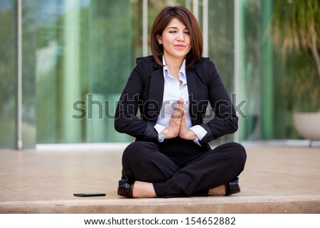 Cute young businesswoman doing some yoga and clearing her mind at work