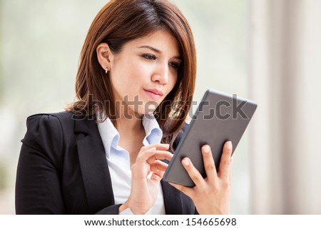 Young Hispanic business woman using a tablet to check her emails