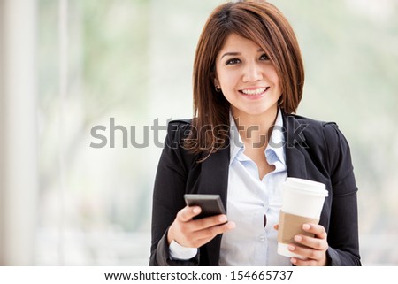 Gorgeous young businesswoman social networking on her cell phone during a coffee break. Lots of copy space