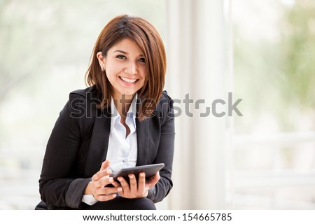 Pretty brunette on a suit working social networking on a tablet computer and smiling