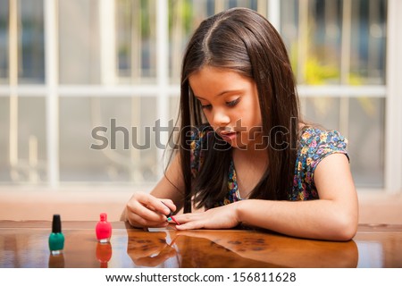 Pretty little girl panting her nails with her mom's nail polish