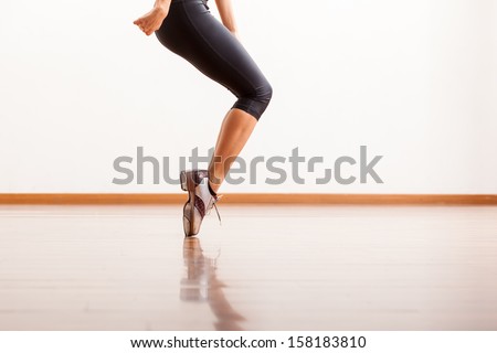 Closeup of a female dancer\'s tap shoes while she performs in a studio