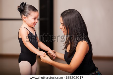Beautiful female dance instructor talking to and coaching one of her students in a dance academy