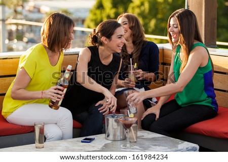 Group of four female friends having fun and drinking alcohol in a terrace in the afternoon