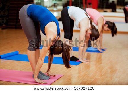Group of young women trying the big toe pose at their yoga class in a gym