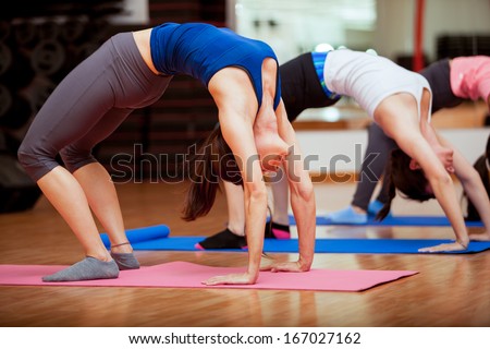 Group of young women arching their backs and trying out a few yoga poses in a gym