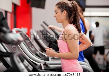 Cute young Latin woman exercising on a treadmill at a gym