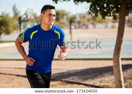 Handsome young man running at a park on a sunny day