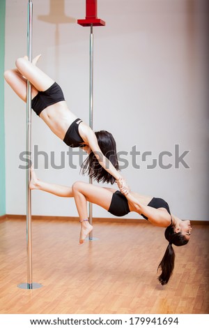 Beautiful pole dancers combining strength and balance for a beautiful routine