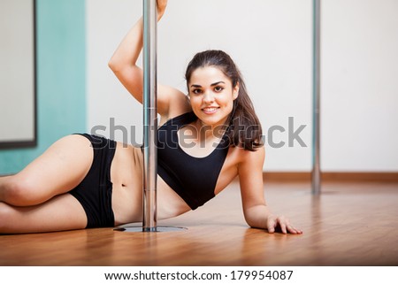 Happy young woman taking a break and relaxing at her pole fitness class