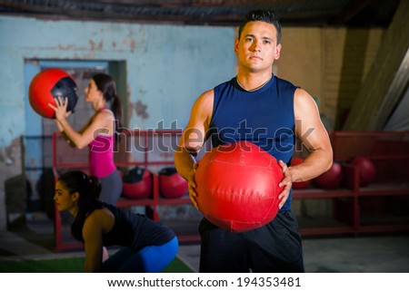 Handsome Latin young man holding a medicine ball in a cross-training gym