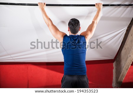 Athletic young man about to pull himself up a bar at a cross-training gym