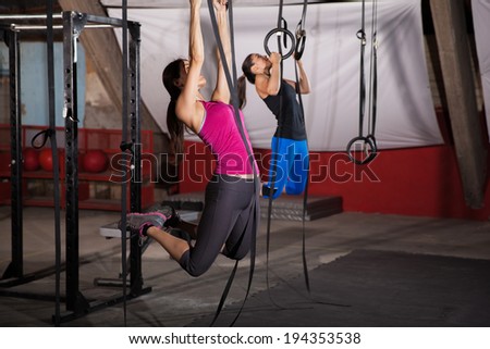 Two women exercising in the gymnastic rings in a cross-training gym