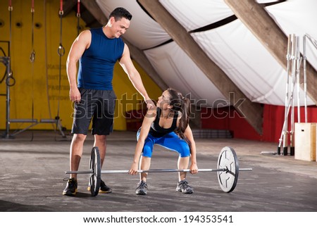 Young Hispanic man giving some advice on her workout to a cute girl in a gym