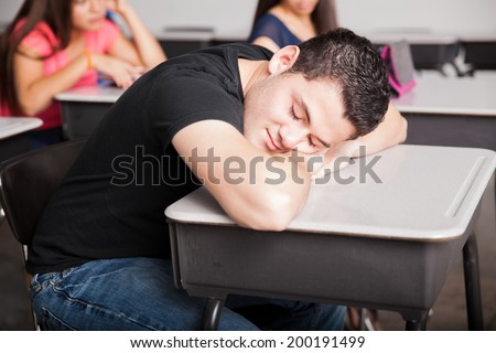 Portrait of a tired high school student sleeping and dreaming during a boring class