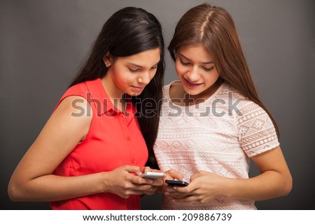 Beautiful couple of teenage friends social networking and sharing photos with their smart phones