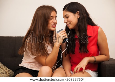 Fun teenage best friends listening to music and singing together at home