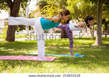Pretty Hispanic young women maintaining balance while doing yoga outdoors