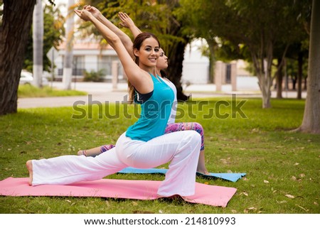 Cheerful young woman and her friend enjoying their yoga practice at a park