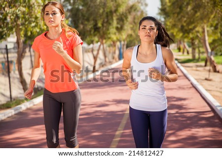 Cute young Hispanic women running together at a running track