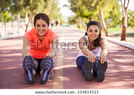 Beautiful young women doing some stretching before going for a run at a running track