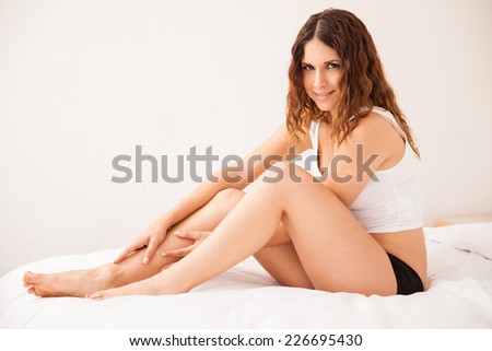 Pretty young Hispanic woman touching her legs and smiling after removing all her hair