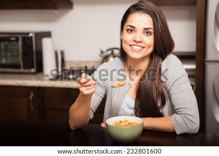 Happy young Latin woman enjoying a bowl of cereal for breakfast at home