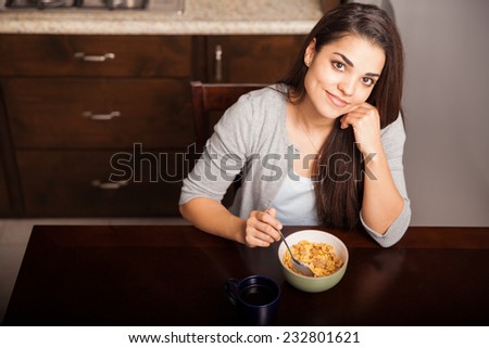 Top view of a cute young woman having a bowl of cereal and coffee for breakfast