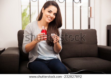 Beautiful Hispanic young woman about to take some cough syrup to feel better
