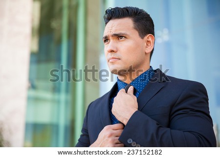 Portrait of a handsome young man in a suit getting ready for an interview and fixing his tie