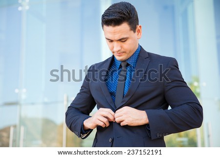 Attractive young businessman buttoning his jacket and fixing his suit before going into an important meeting