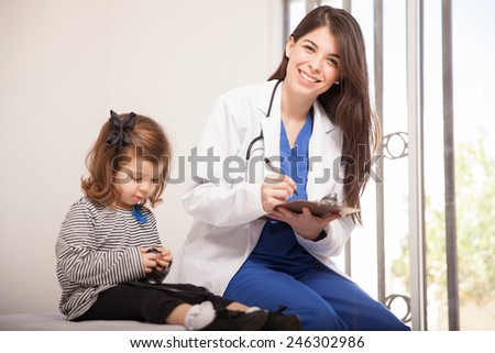 Portrait of a gorgeous pediatrician loving her job and sitting next to a little girl