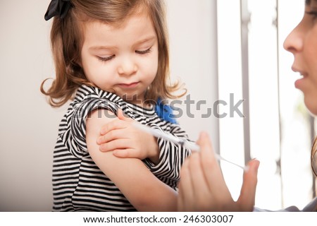 Closeup of a cute little girl getting a flu shot at a doctor\'s office