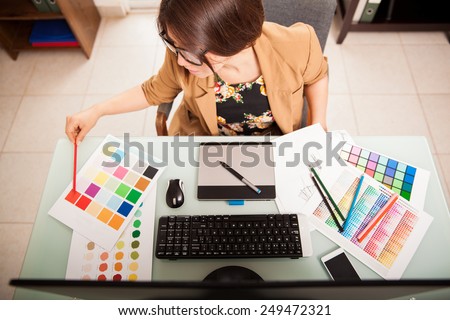 Top view of a young graphic designer working on a desktop computer and using some color swatches