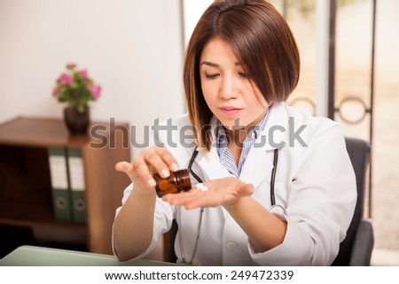 Pretty female doctor pouring some vitamins on her hand while sitting in an office