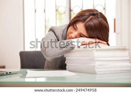 Cute young business woman falling asleep at the office after long hours of work