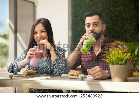 Attractive young couple having some smoothies and sandwiches during a lunch date
