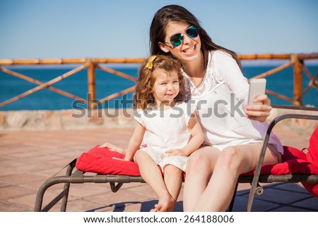 Portrait of a young mother and her daughter taking a selfie with a smartphone and smiling
