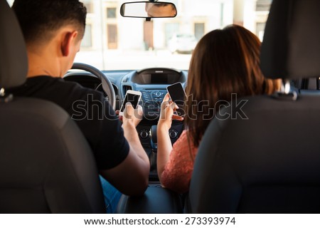Rear view of a young couple texting and driving while ignoring the road