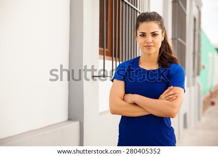 Portrait of a pretty young woman in sporty outfit and her arms crossed, about to work out in the city