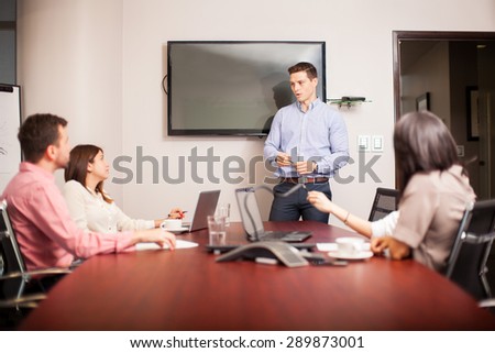 Handsome young man dressed casually and giving a sales pitch in a meeting room