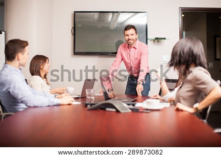 Portrait of an attractive young man talking to the rest of his team and smiling