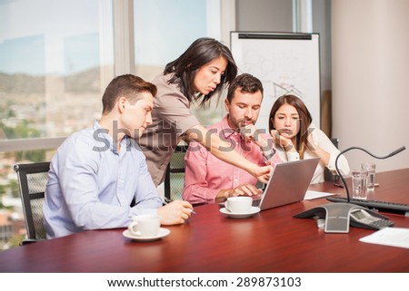 Group of four people looking at a laptop computer and working in a meeting room