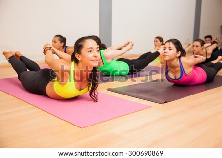 Pretty female yoga instructor and her students doing the locust pose during class
